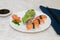 Salmon nigiri sushi and shrimp rolls with avocado on white plate with decoration.