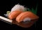 Salmon nigiri sushi. Two pieces of Japanese salmon sushi on a black reflective surface served with wasabi and white radish.