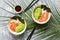Salmon poke bowl with rice,nori, avocado , black sesame seeds on a gray background decorated with tropical leaves. Top view, flat