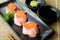 Salmon Roe on Hamachi sushi on black plate along with Japanese sauce and green leaf decoration, Japanese food, close up at sushi