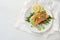 Salmon roll with pea puree filling on rocket salad with lemon slices and herb garnish on a white table, healthy slimming with low