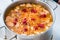 Salmon soup with carrot and raspberry in stainless pot