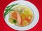 Salmon soup with carrots, peas, onions, herbs