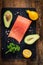 Salmon steak, avocados, lemons, parsley and spices on wooden cutting board