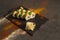 Salmon Sushi roll with avocado, red caviar on black plate, spices on dark background