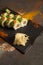 Salmon Sushi roll with avocado, red caviar on black plate, spices on dark background