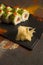 Salmon Sushi roll with avocado, red caviar on black plate, spices on dark background