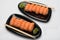 Salmon sushi, wooden sticks and wasabi on two black ceramic plates of a bean-shaped form
