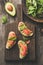 Salmon toast with avocado on wooden cutting board, top view