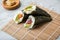 Salmon, tuna fish and Surimi avocado Temaki sushi with pickled ginger on mat and marble background