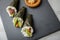 Salmon, tuna fish and Surimi avocado Temaki sushi with pickled ginger and wasabi on slate plate and marble background