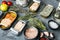 Salmon, tuna, trout mackerel and anchovy - Canned fish in tin cans, on gray background with herbs and ingredients