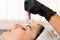 Salon cosmetology. Beautician in rubber gloves does procedure of apparatus fractional mesotherapy of woman`s face. Close up of