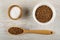 Salt in bamboo bowl, buckwheat in white bowl, spoon with raw buckwheat on table. Top view