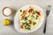 Salt in bowl, pepper shaker, white dish with omelette with tomato and parsley, fork on table. Top view