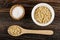 Salt in bowl, spoon with oat flakes, flakes in white bowl on wooden table. Top view