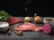 Salt crystals fall on a piece of beef on a wooden table.