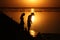 On a salt lake in the setting sun, family, father with a hat, mother and small child on the horizon with a silhouette walk along