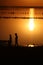 On a salt lake in the setting sun, family, father with a hat, mother and small child on the horizon with a silhouette walk along