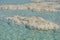 Salt ledges in the turquoise clear water on the beach of the Dead Sea in Israel. Flakes of salt under the water, climate change