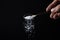 Salt is poured from a spoon on a black background. Excessive salt intake.