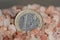 Salt price. Large crystals of pink Himalayan salt, close-up. A coin in a pile of salt as a symbol of rising prices.