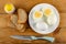 Salt, slices of bread, plate with whole eggs and halves of boiled egg, knife on wooden table. Top view