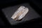 Salted boneless fillets of wild-caught Atlantic Herring arranged on natural black stone. Clupea harengus.