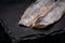 Salted boneless fillets of wild-caught Atlantic Herring arranged on natural black stone. Clupea harengus.