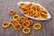 Salted bread rings in oblong plate and scattered rings on mat