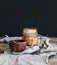 Salted caramel sauce in a rustic glass jar and brown ceramic cup on wooden desk