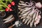 Salted fishes sprat marinated with spices, salt, radish and slice of bread on plate over dark stone background. Mediterranean food