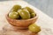 Salted giant green olives in olive bowl on wooden