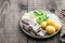 Salted herring with boiled potatoes and quial eggs on a white plate on wooden table