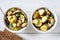 Salted milk mushrooms and pickled cucumbers in bowls on a white wooden table