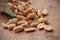 Salted peanuts falling from glass container on wooden