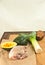 Salted and peppered raw, organic, chicken breast, washed leek, and potato, and split acorn squash, on a bamboo wood cutting board,