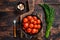 Salted Pickled cherry tomatoes in a pan with herbs and dill. Dark wooden background. Top view