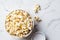 Salted popcorn in white bowl, white marble background
