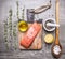 Salted salmon fillet on a cutting board with rosemary, pepper, oil, lemon and a wooden spoon salt on wooden rustic backgroun