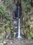 Salto do Cabrito beautiful waterfall at hiking trail falling a from rock cave in green forest, Sao Miguel, Azores