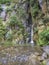 Salto do Cabrito beautiful waterfall at hiking trail falling a from rock cave in green forest, Sao Miguel, Azores