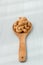 Salty cashew nuts in wood spoon on gray