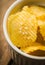 Salty grooved chips in white ceramic bowl on the rustic background. Selective focus. Shallow depth of field