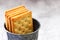 Salty rectangular crackers in a galvanized bucket on a gray background.