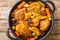 Salvadoran chicken stew with chicha, prunes, carrots, potatoes, olives and onions close-up in a frying pan. Horizontal top view