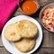 Salvadoran pupusas with coleslaw and tomato sauce on wooden background