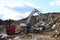 Salvaging and recycling building and construction materials. Industrial waste treatment plant. Excavator work at landfill with con