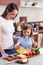 Same Sex Female Couple With Daughter Preparing School Lunchbox At Home Together