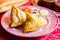 Samosa is a fried or baked dumpling with savory filling, such as seasoned potatoes, onions, peas, meat, or lentils.